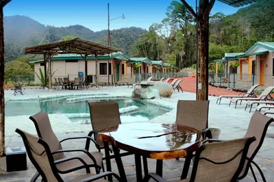 a table and chairs in front of a swimming pool at Coffee Pickers Village By Hacienda Orosi in Cartago