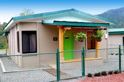 a small house with a green door and a fence at Coffee Pickers Village By Hacienda Orosi in Cartago