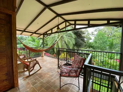 a porch with a hammock and chairs on a balcony at Serenity in Fortuna