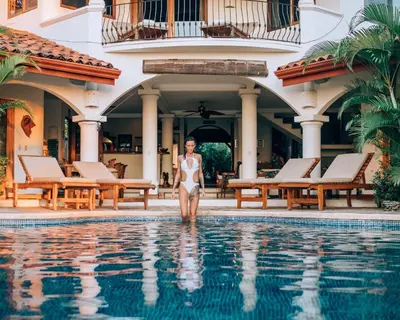 a woman in a white bikini walking out of a swimming pool at Los Altos de Eros - Adults Only in Playa Avellana
