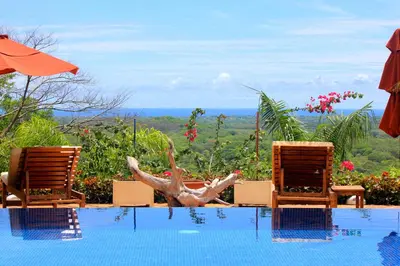 a swimming pool with two chairs and an umbrella at Los Altos de Eros - Adults Only in Playa Avellana