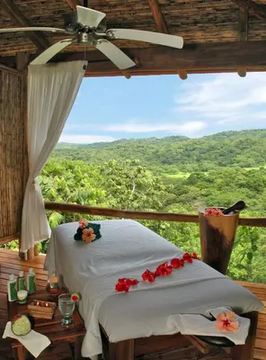 a bed in a room with a view of a forest at Los Altos de Eros - Adults Only in Playa Avellana