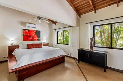 a bedroom with a large bed and two windows at Los Altos de Eros - Adults Only in Playa Avellana