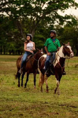 a man and a woman riding horses in a field at Hacienda Pinilla Vacation Rentals in Tamarindo