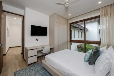 a bedroom with a bed and a desk with a television at Hacienda Pinilla Vacation Rentals in Tamarindo