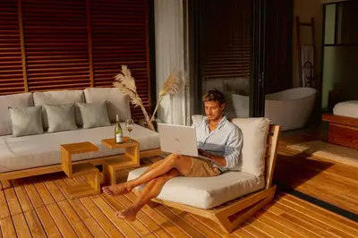 a man sitting in a chair with a laptop at The L Design Villa in Carmen