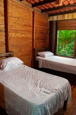 two beds in a wooden room with a window at Cabaña Ave Del Paraiso in Cartago
