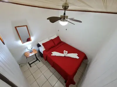 a bedroom with a red bed with two shoes on it at Cabinas Guayabón #3, AC, La Fortuna Volcán Arenal in Fortuna