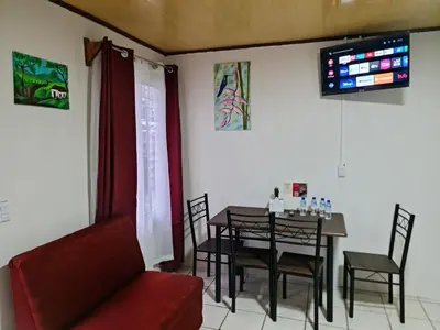 a dining room with a table and a red couch at Cabinas Guayabón #3, AC, La Fortuna Volcán Arenal in Fortuna