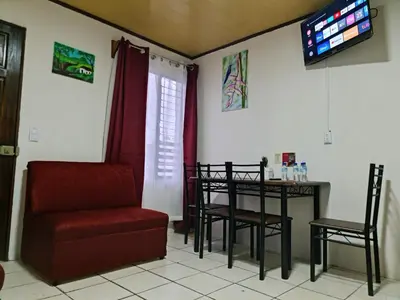 a living room with a chair and a table and a television at Cabinas Guayabón #3, AC, La Fortuna Volcán Arenal in Fortuna