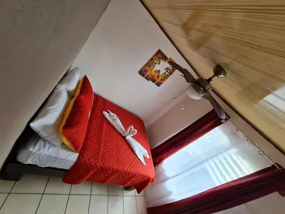 a bedroom with a bed with a red blanket and a window at Cabinas Guayabón #3, AC, La Fortuna Volcán Arenal in Fortuna