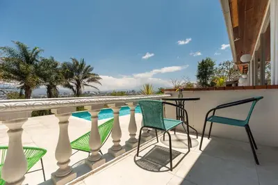 a balcony with chairs and a table and a pool at Posada el Quijote in San José