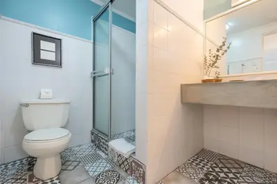 a bathroom with a toilet and a glass shower at Posada el Quijote in San José