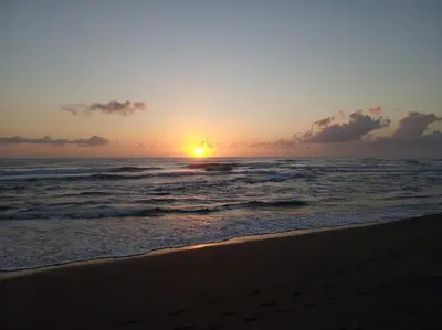 a sunset on a beach with the ocean at Tortuguero Adventures Beach House in Tortuguero