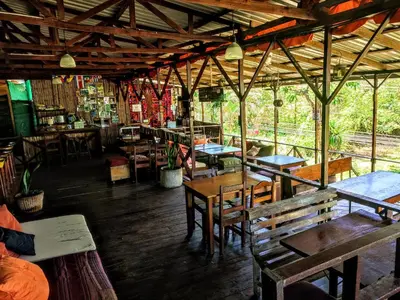 a restaurant with wooden tables and chairs in a room at Hostel Plinio in Manuel Antonio