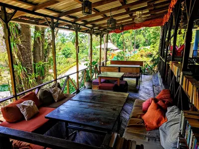 a room with benches and tables in a tree house at Hostel Plinio in Manuel Antonio