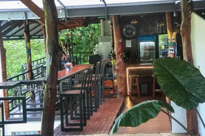 a restaurant with a bar with wooden tables and chairs at Hostel Plinio in Manuel Antonio