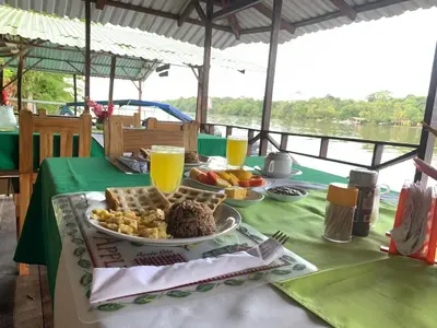 a table with a plate of food and orange juice at All Rankins Eco-Lodge in Tortuguero