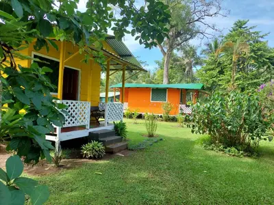 a yellow and orange house with a bench in the yard at All Rankins Eco-Lodge in Tortuguero