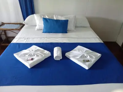 a bed with two pillows and towels on it at All Rankins Eco-Lodge in Tortuguero