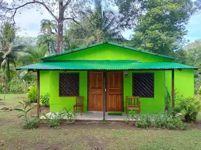 a green house with two chairs in front of it at All Rankins Eco-Lodge in Tortuguero