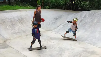 two children are standing on skateboards at a skate park at Casa Coco Playa Marbella with AC, Swimming Pool, Skate Bowl & walking distance Beach for Surfers and Nature Lovers in Marbella