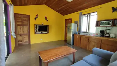 a kitchen with yellow walls and a table and a refrigerator at Casa Coco Playa Marbella with AC, Swimming Pool, Skate Bowl & walking distance Beach for Surfers and Nature Lovers in Marbella
