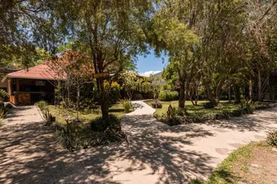 a path in a park with trees and a building at Colinas del Miravalles Hotel & Hot Springs in Hacienda Guayabo