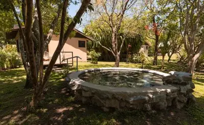 a large stone pond in a yard with trees at Colinas del Miravalles Hotel & Hot Springs in Hacienda Guayabo