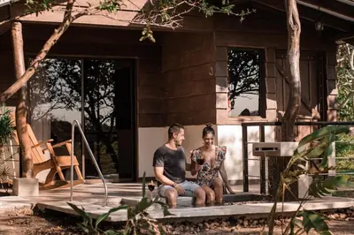 a man and woman sitting on the porch of a house at Colinas del Miravalles Hotel & Hot Springs in Hacienda Guayabo