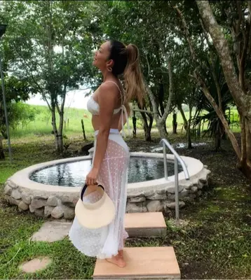a woman in a white dress standing in front of a pond at Colinas del Miravalles Hotel & Hot Springs in Hacienda Guayabo