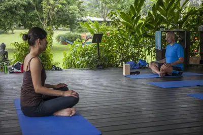 a man and a woman sitting on mats in a yoga class at Hotel Arenal Springs Resort & Spa in Fortuna