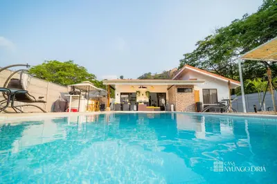 a large blue swimming pool in front of a house at Bungalow with private pool only 15min from Tamarindo Beach in Tamarindo
