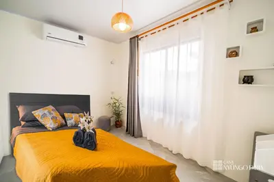 a bedroom with a bed with an orange bedspread and a window at Bungalow with private pool only 15min from Tamarindo Beach in Tamarindo
