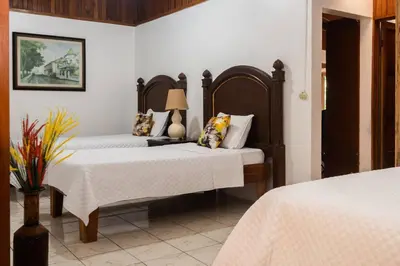 a bedroom with two beds with white sheets and a lamp at Gateway to Paradise in Tilarán