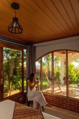 a woman sitting in a chair in a room with windows at Gateway to Paradise in Tilarán
