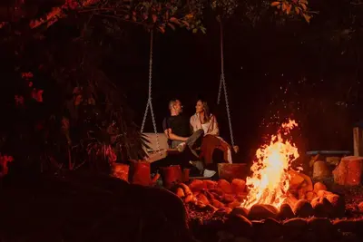 two people sitting on a swing over a fire at Gateway to Paradise in Tilarán