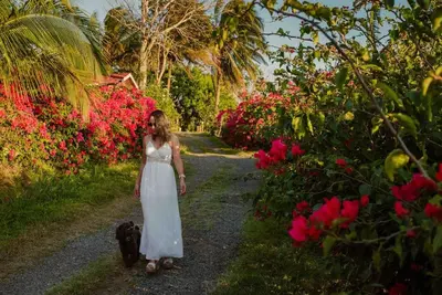 a woman in a white dress walking down a path with flowers at Gateway to Paradise in Tilarán