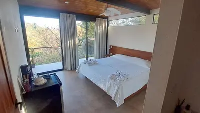 a bedroom with a white bed and a large window at Villa Gaspar Terrazas in Playa hermosa