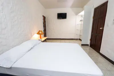 a bedroom with a large white bed and a television at Hotel Flor Blanca in Manuel Antonio