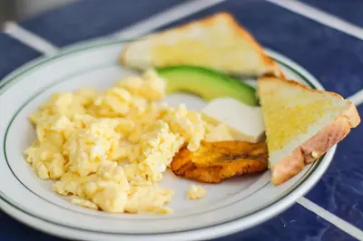 a plate of breakfast food with scrambled eggs and toast at Hotel Flor Blanca in Manuel Antonio