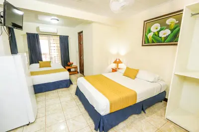 a hotel room with two beds and a tv at Hotel Flor Blanca in Manuel Antonio