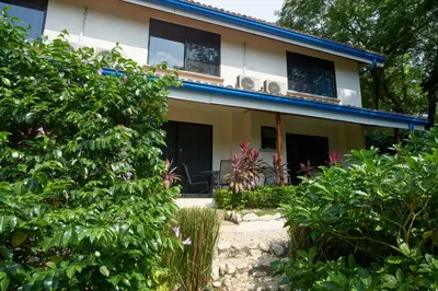a house with a bunch of plants in front of it at Tamarindo Blue Apartments in Tamarindo