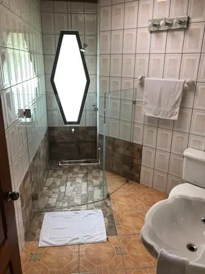 a bathroom with a shower with a mirror and a sink at Vistaverde Lodge in Monteverde Costa Rica
