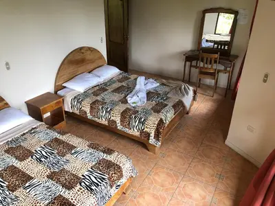 a bedroom with two beds and a table and a chair at Vistaverde Lodge in Monteverde Costa Rica