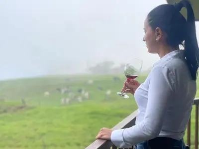 a woman holding a glass of wine looking at a field at Cabaña Montaña de Sueños in Quesada