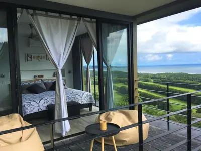 a bedroom with a balcony with a bed and the ocean at La Colina Pura Vista in Bejuco