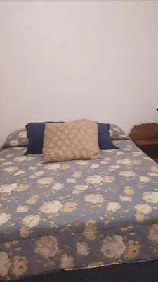 a bed with a floral comforter with a pillow on it at Don Carlos Place LOWER UNIT in Alajuela City