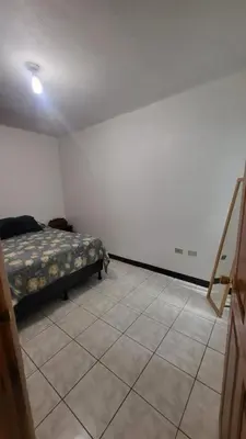 a bedroom with a bed and a tiled floor at Don Carlos Place LOWER UNIT in Alajuela City