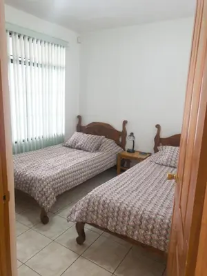 a bedroom with two beds and a window at Don Carlos Place LOWER UNIT in Alajuela City